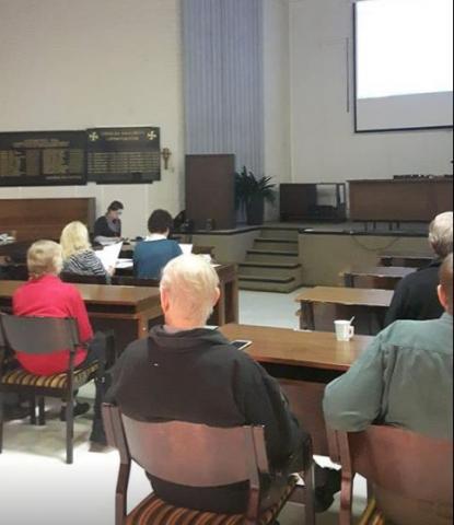 Ihmisiä valtuustosalissa selkä kuvaajaan päin